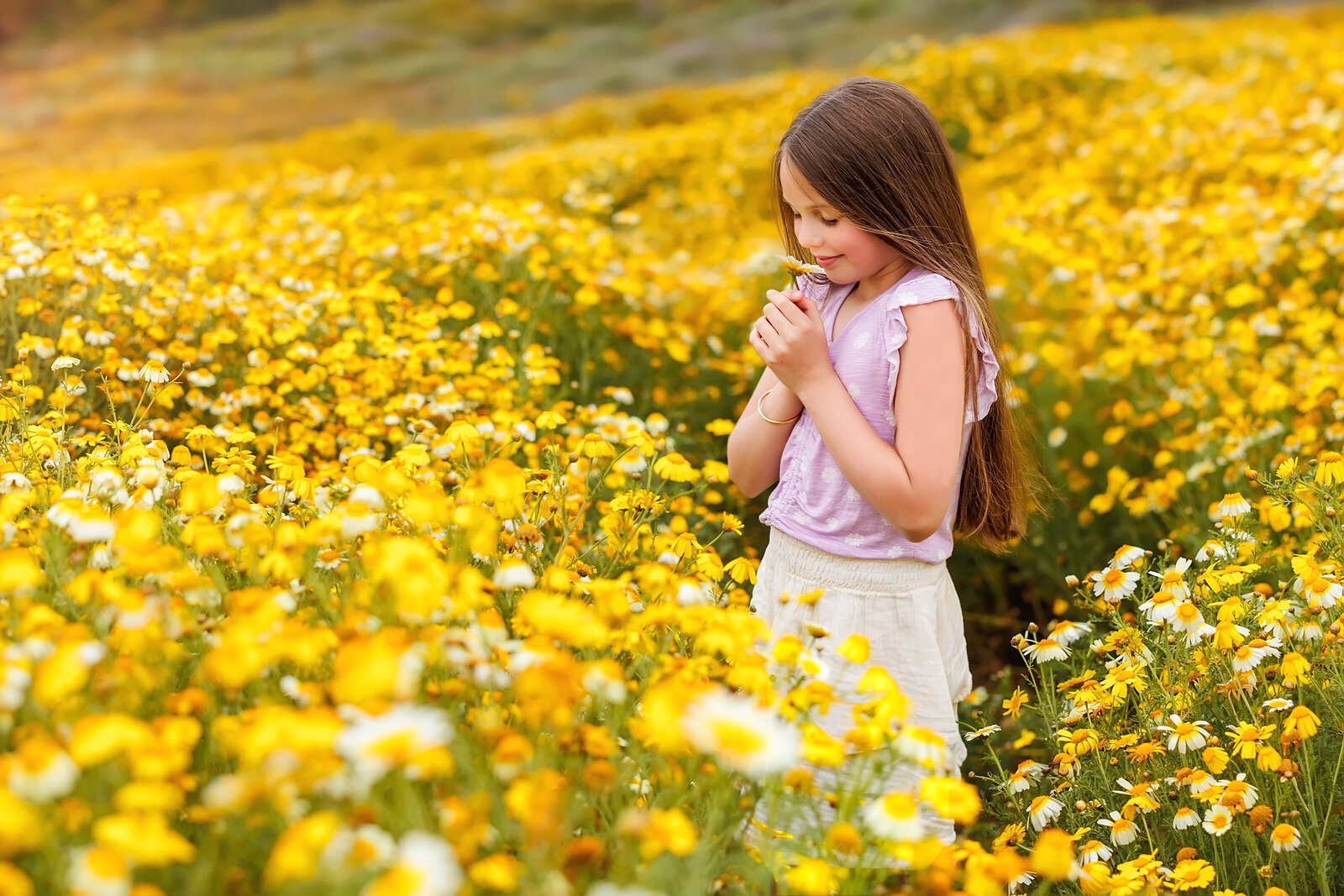 Portrait of young girl smelling a flower in a wild flower field in La Jolla California