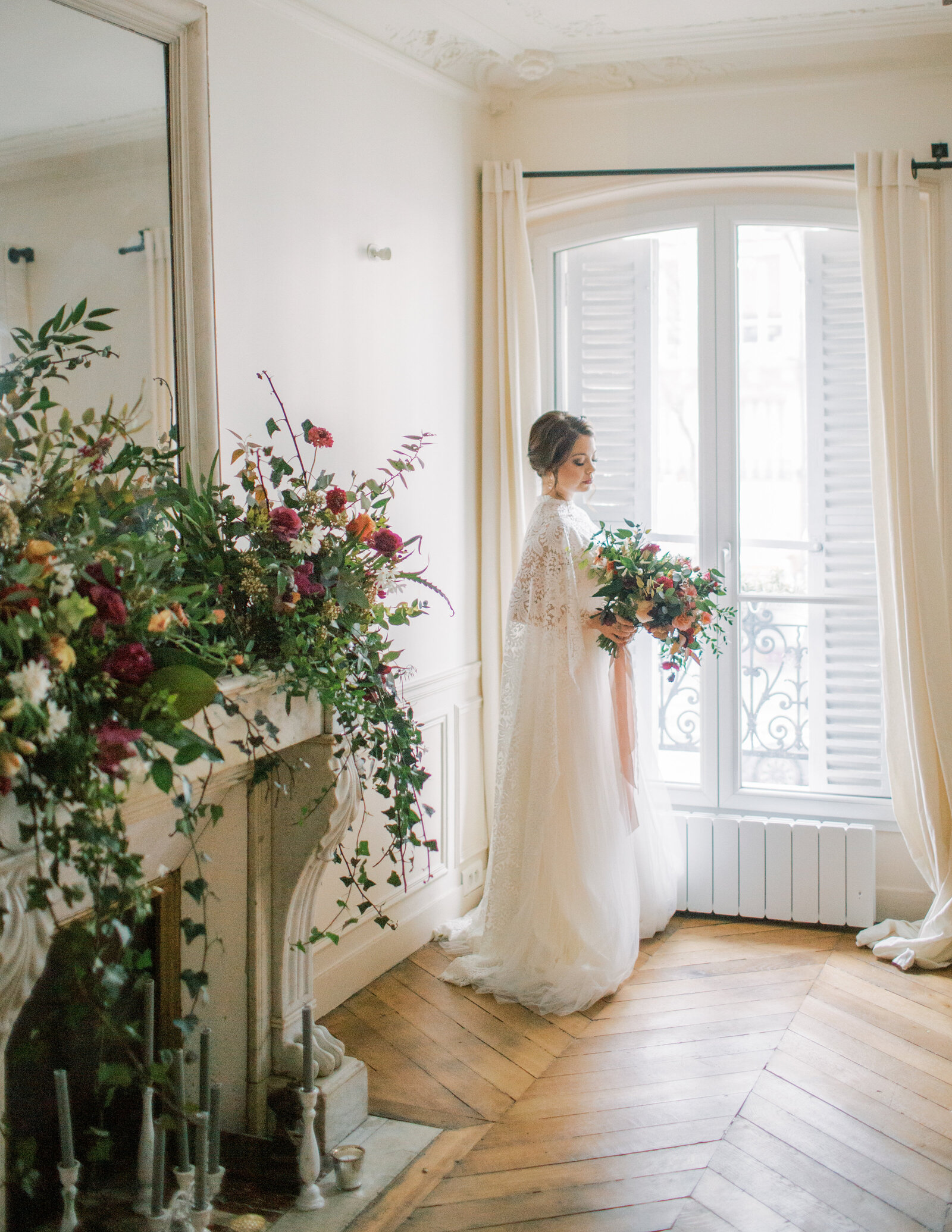 bride holding a bouquet and looking out the window in Paris apartment