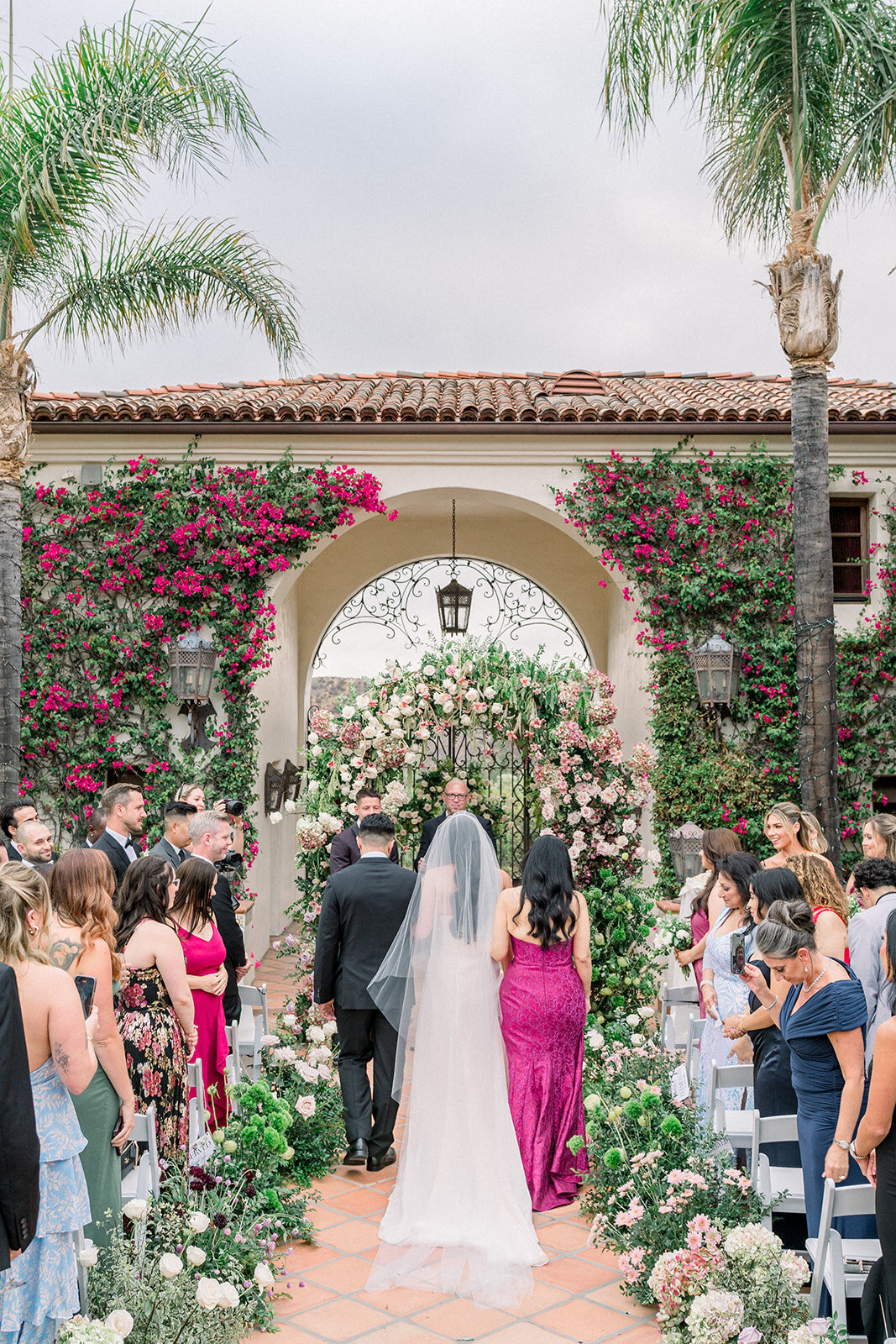 Bride walks down the tiled aisle framed by palms at Hummingbird Nest Ranch in a timeless editorial wedding moment.