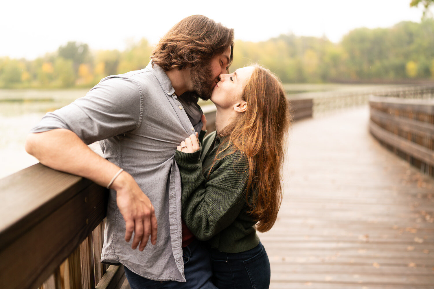 Long haired man and woman kiss on a bridge on a rainy day in Eagan, Minnesota.
