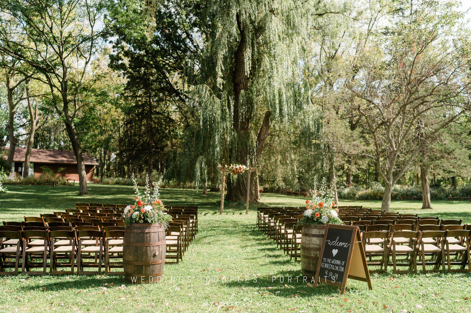 an outdoor wedding ceremony set up under the willow tree at barnwood events in madison, winconsin.