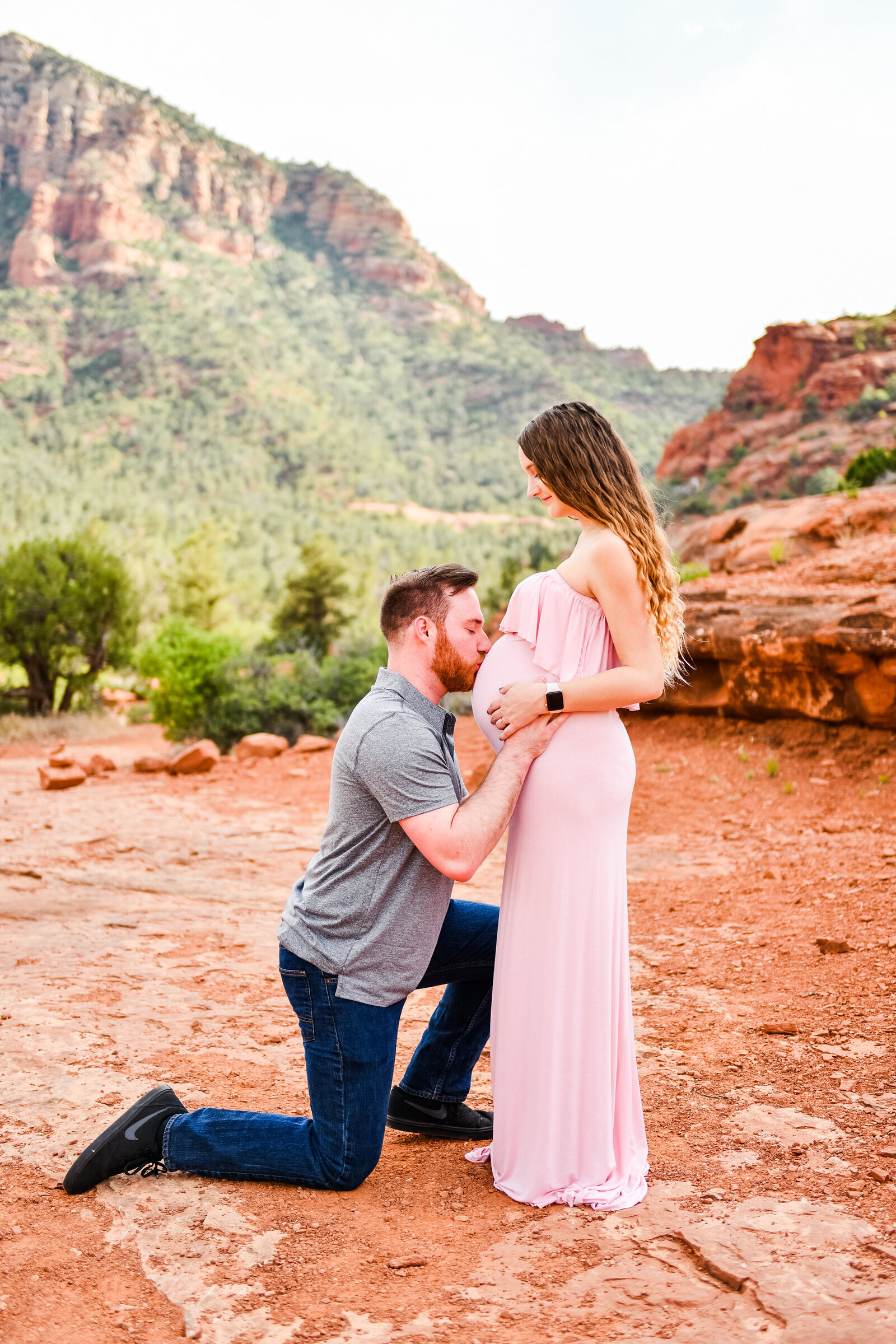Couple in Sedona red rocks kissing belly pregnant announcement pregnancy photography