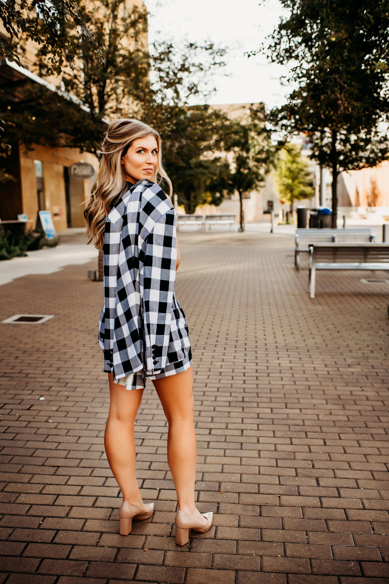 Branding Photographer, a woman wears a large flannel shirt and heels as she stands in town