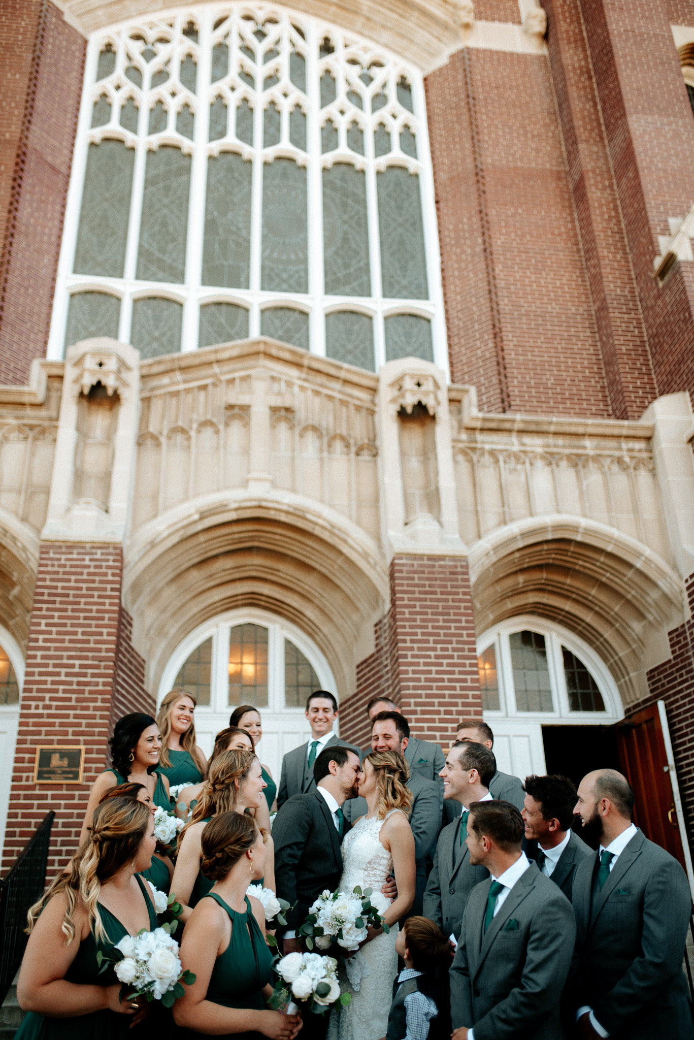 Gorgeous cathedral in Denver Co, photo of bride and groom kissing on the steps surrounded by their bridal party