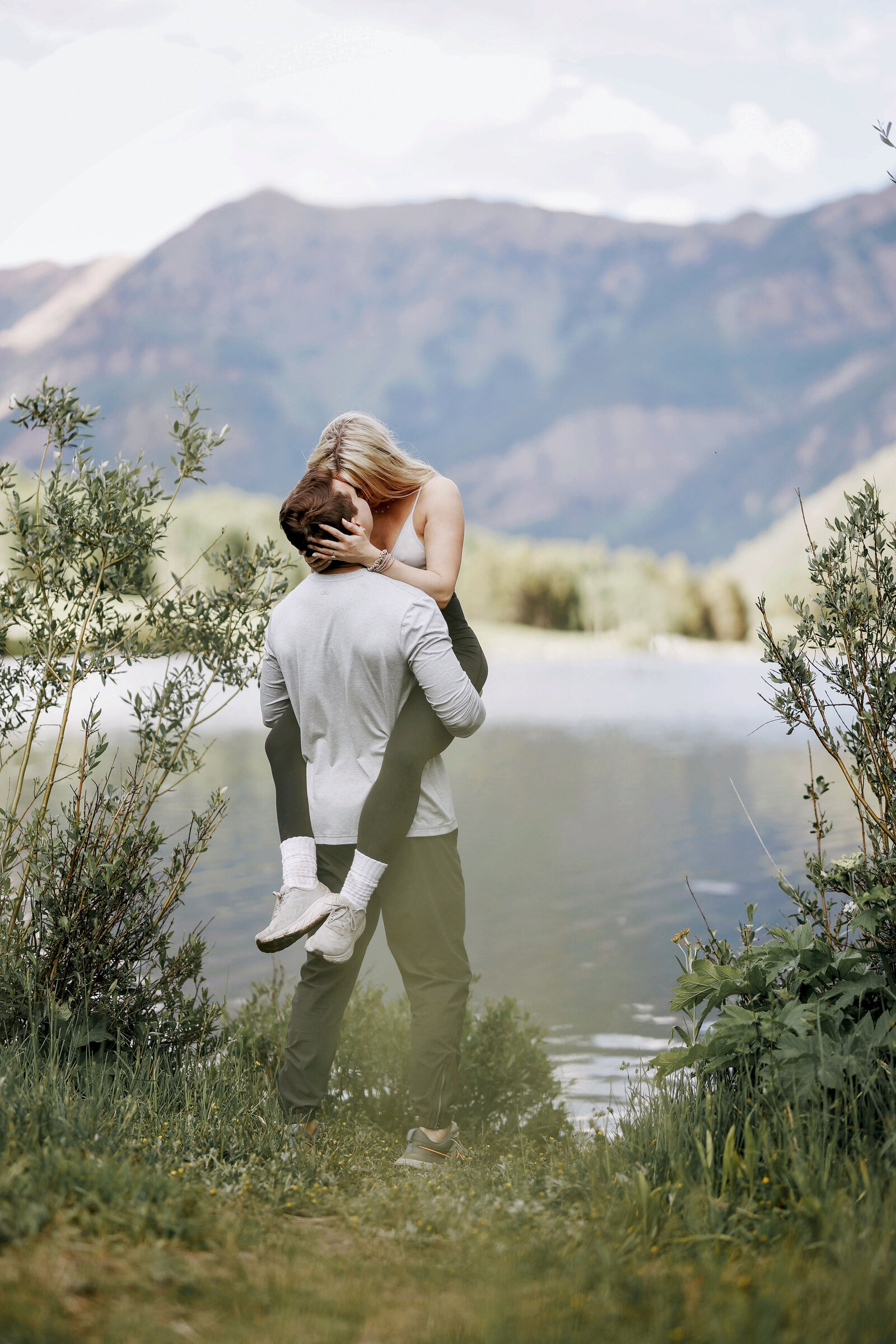 An adorable and happy couple kiss as he picks her up and swings her around in front of Maroon lake, at Maroon Bells.