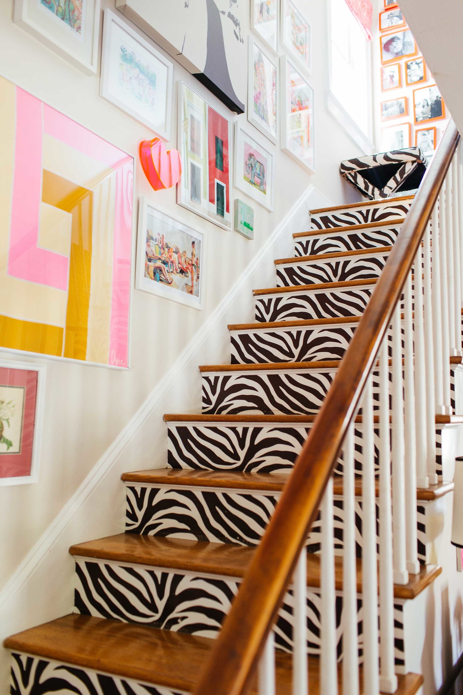 A zebra staircase with a gallery wall of art and photos.