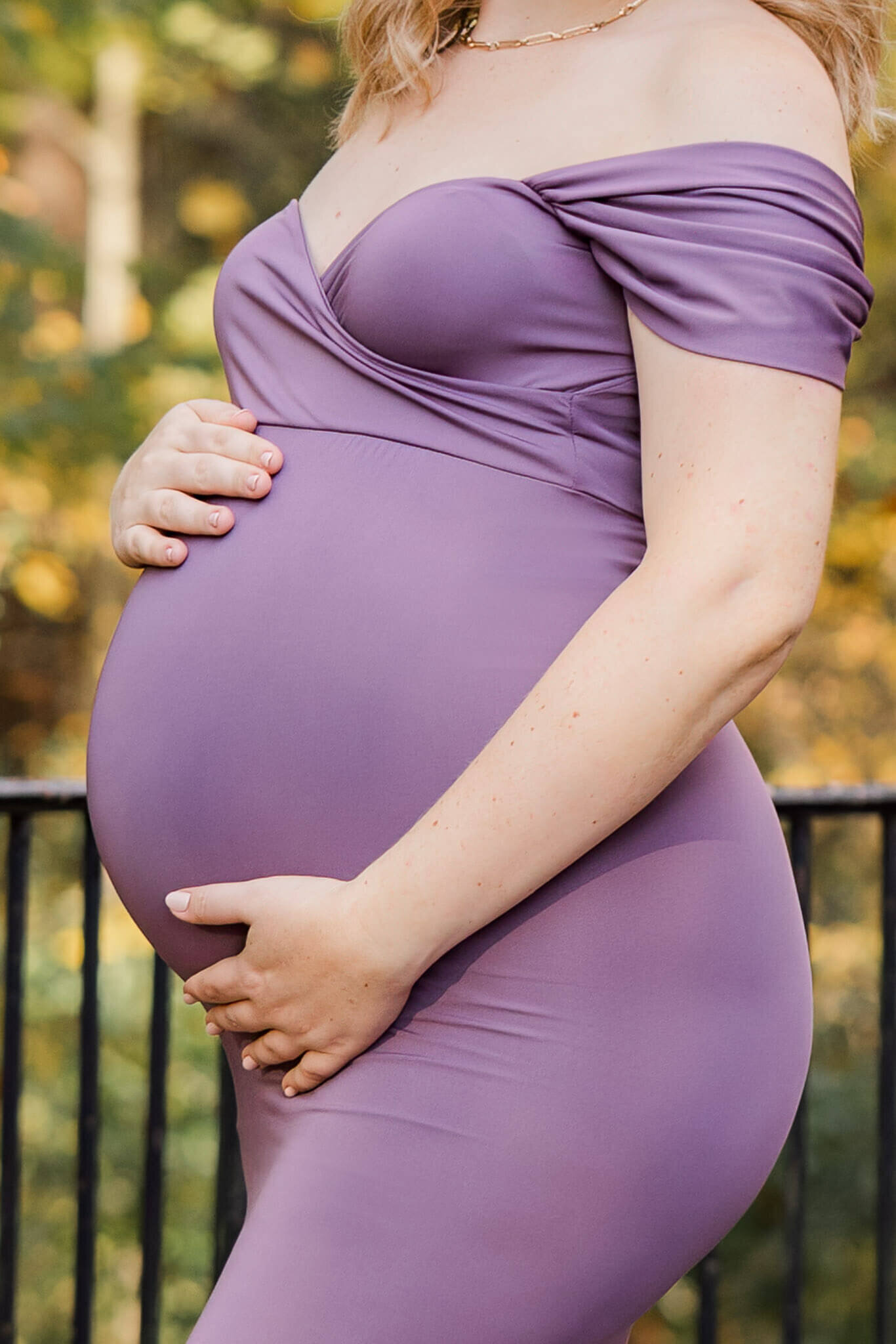 A close-up of a pregnant woman's belly during her maternity portraits at Ellanor C. Lawrence Park.