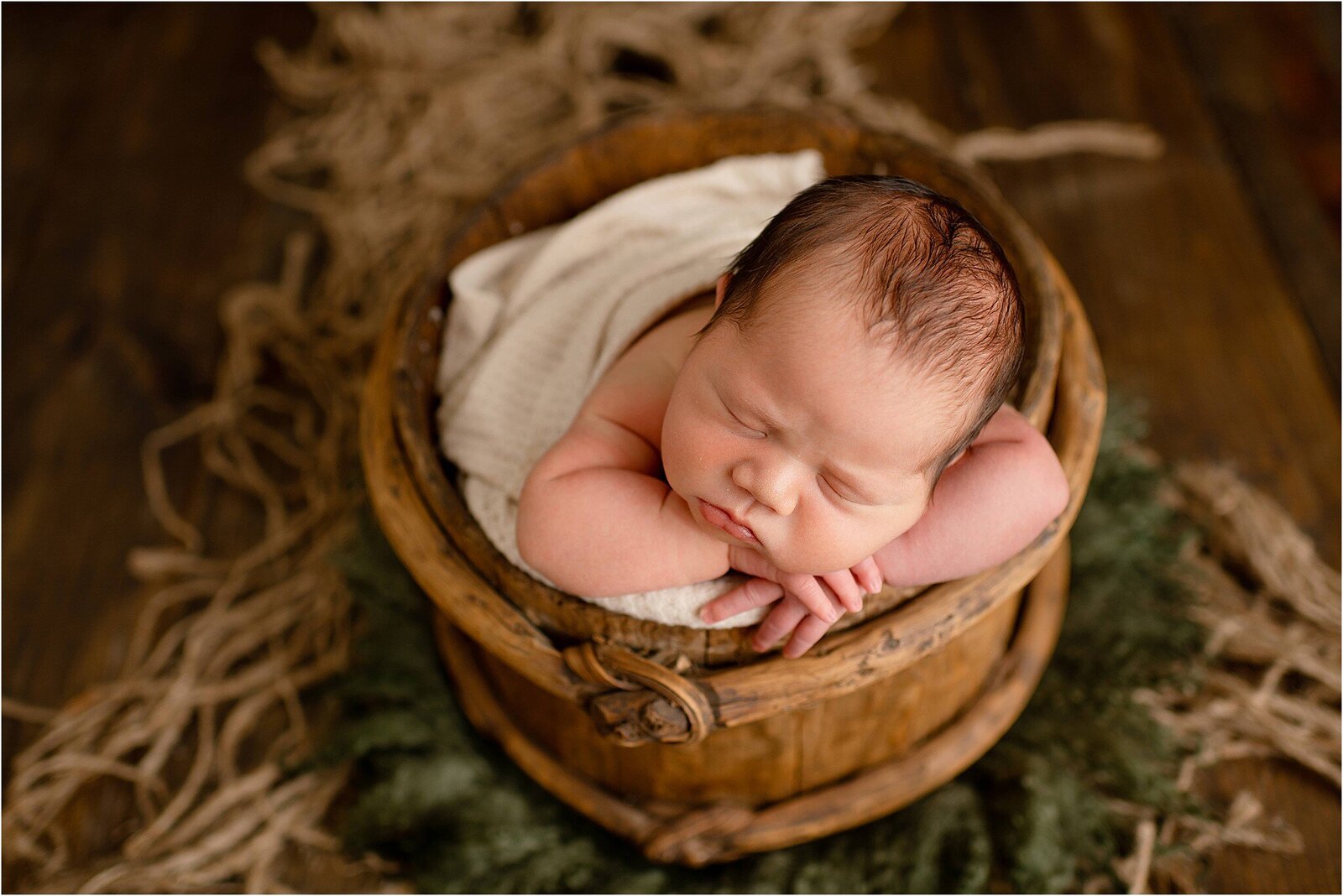 newborn boy in natural wood bucket