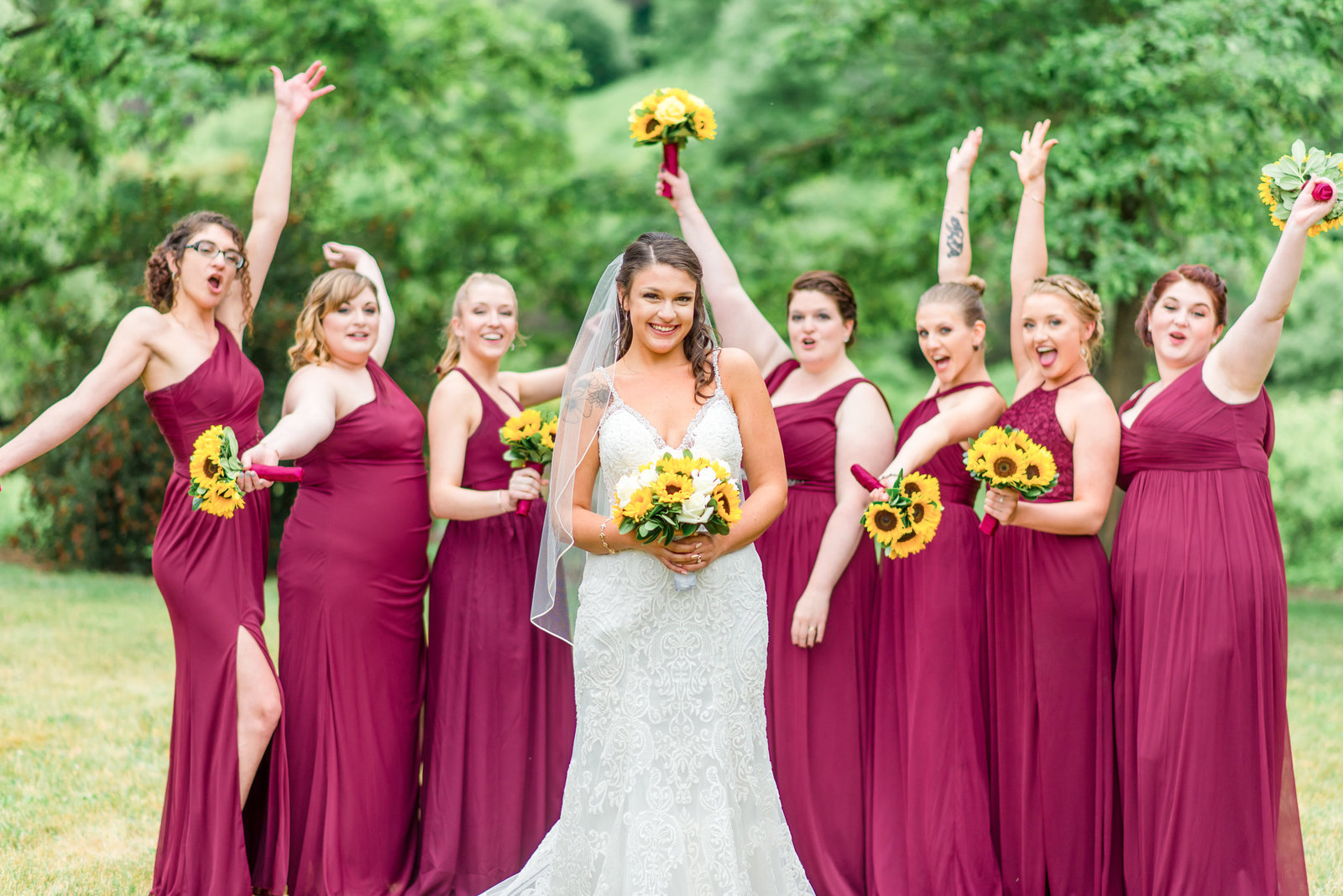Bridesmaids in plum colored dresses cheer for the bride