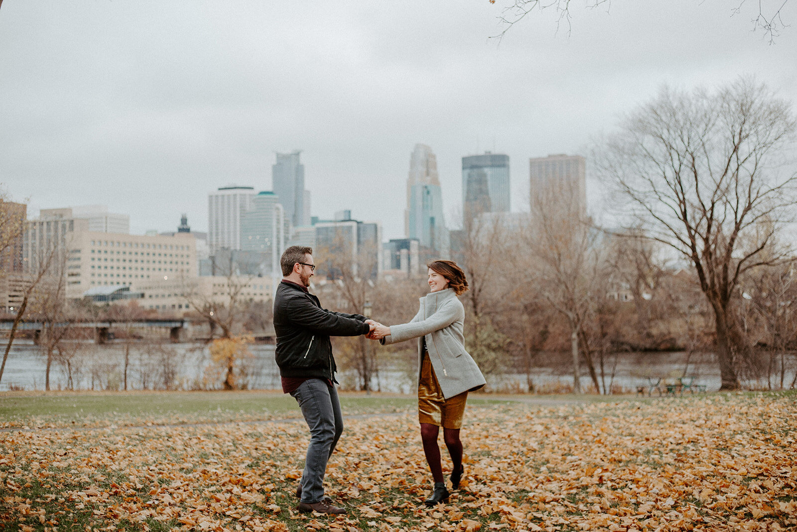 Couple holding hands spinning during their fall engagement session in Minneapolis