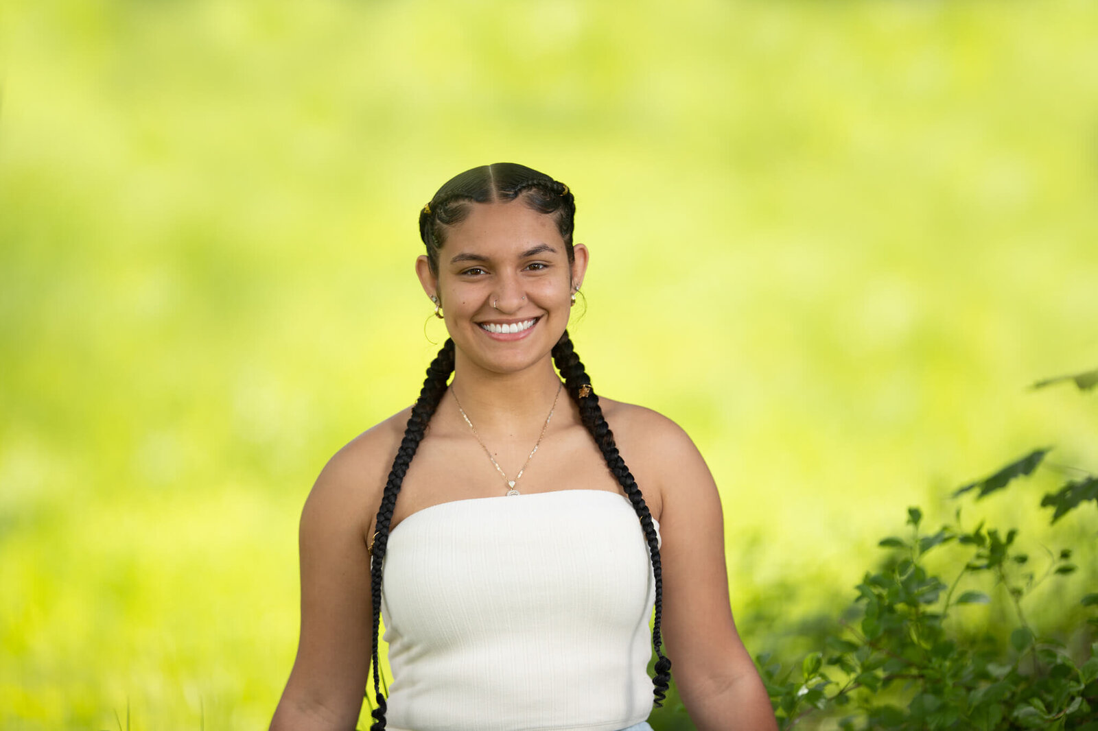 High school senior portrait photography in Clinton MA  of female in a white top smiling with yellow background