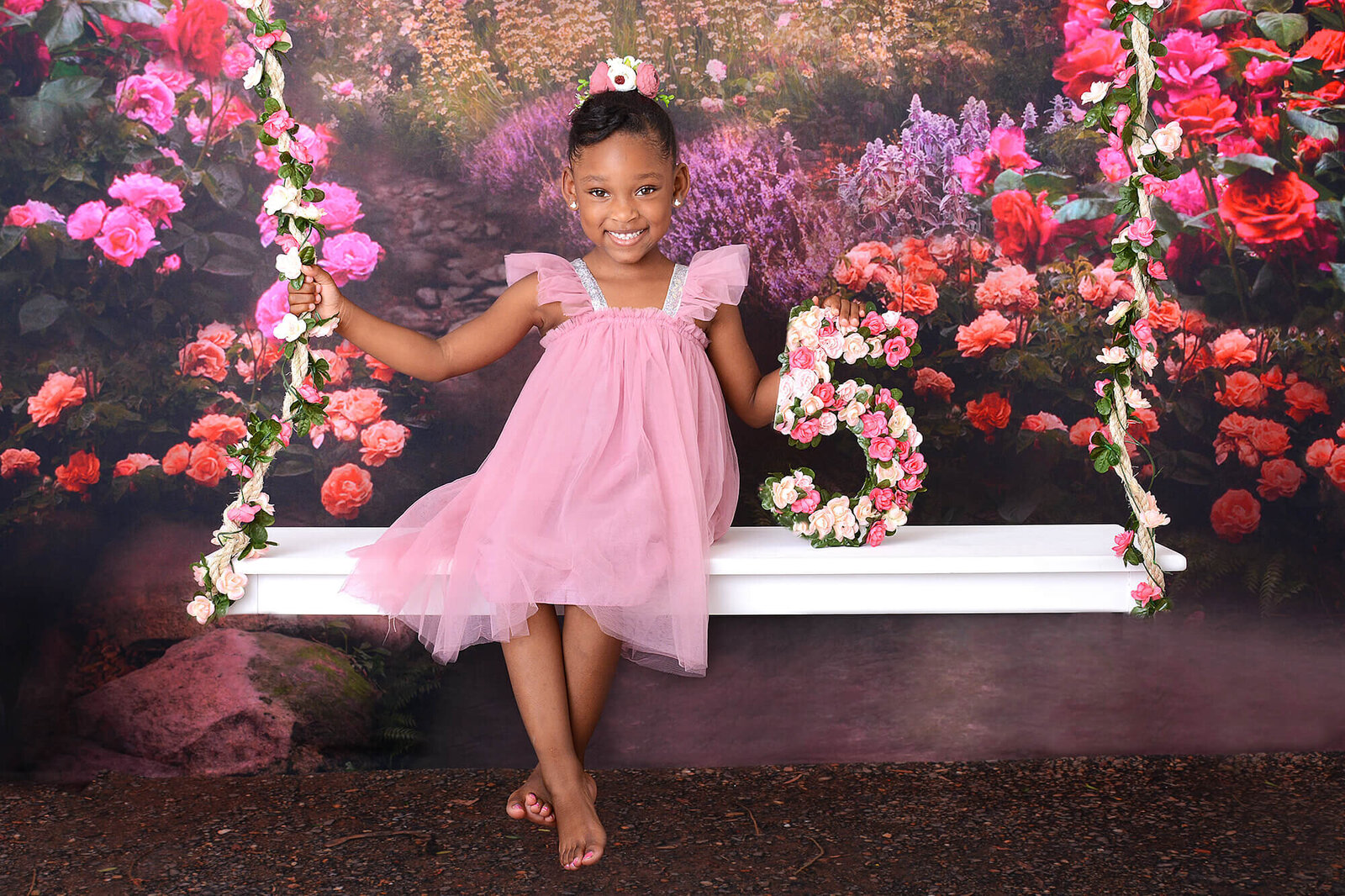 girl smiles with a floral 5 at her fifth birthday photoshoot