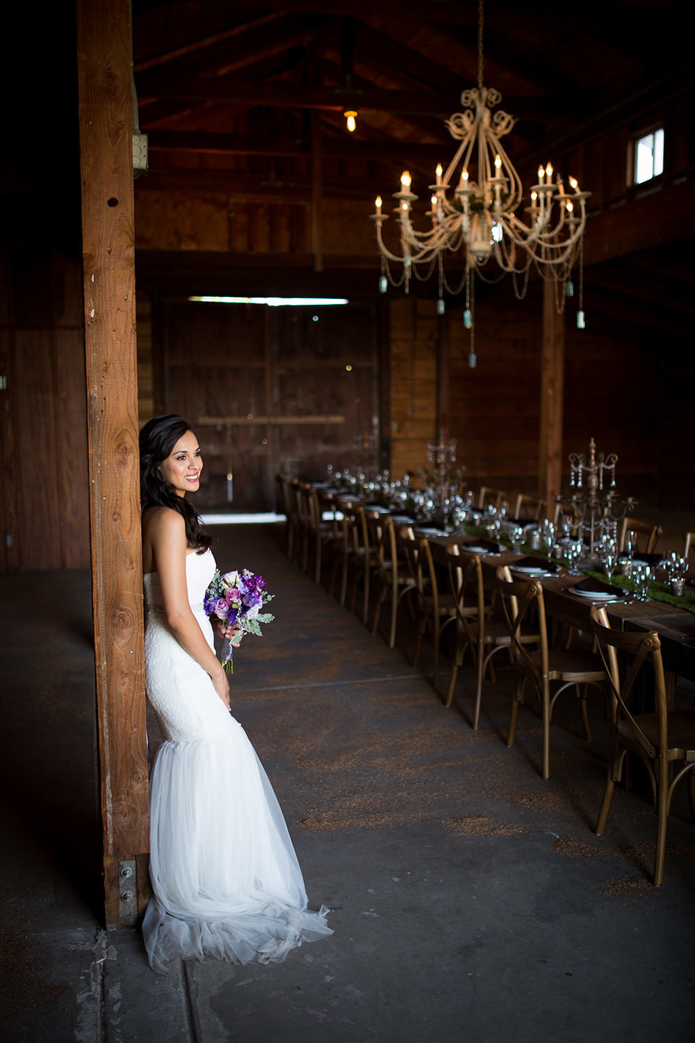 bride in rustic barn with farm tables