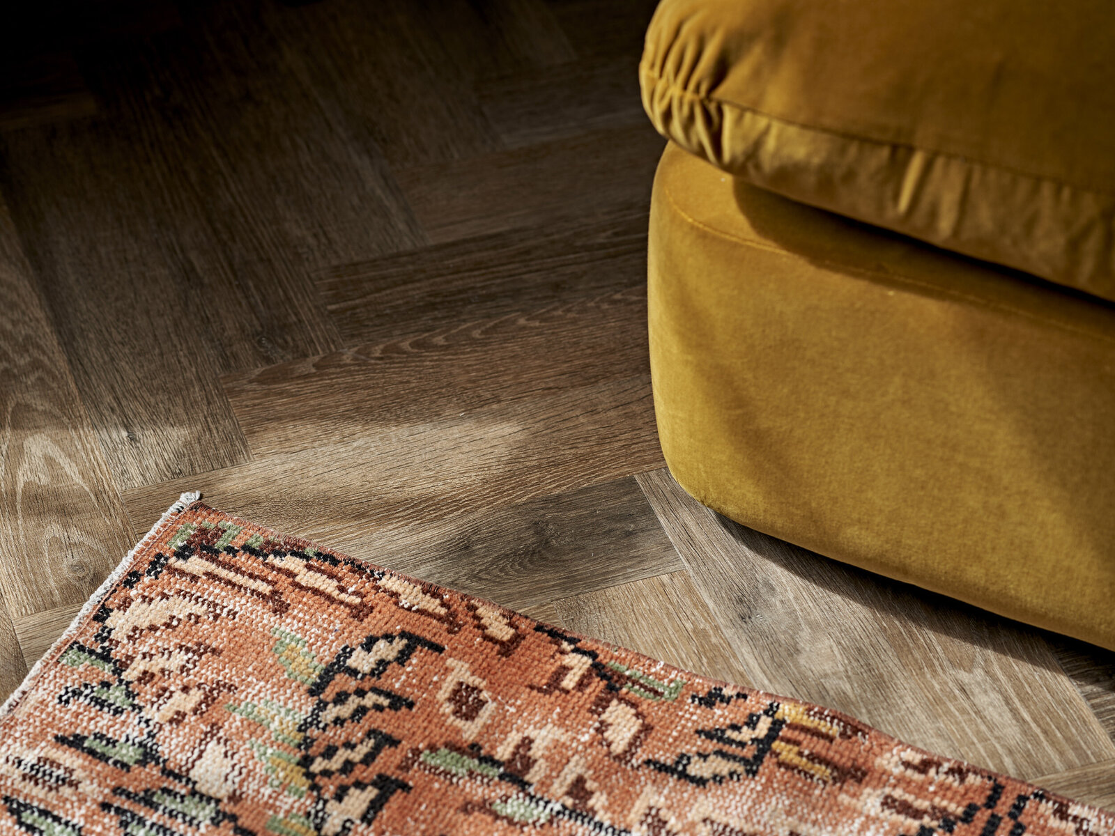 Peach and floral rug on wooden floor with mustard yellow ottoman