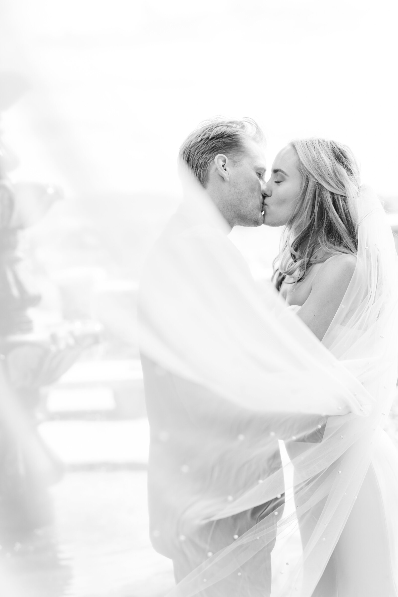 black and white image of bride and groom kissing