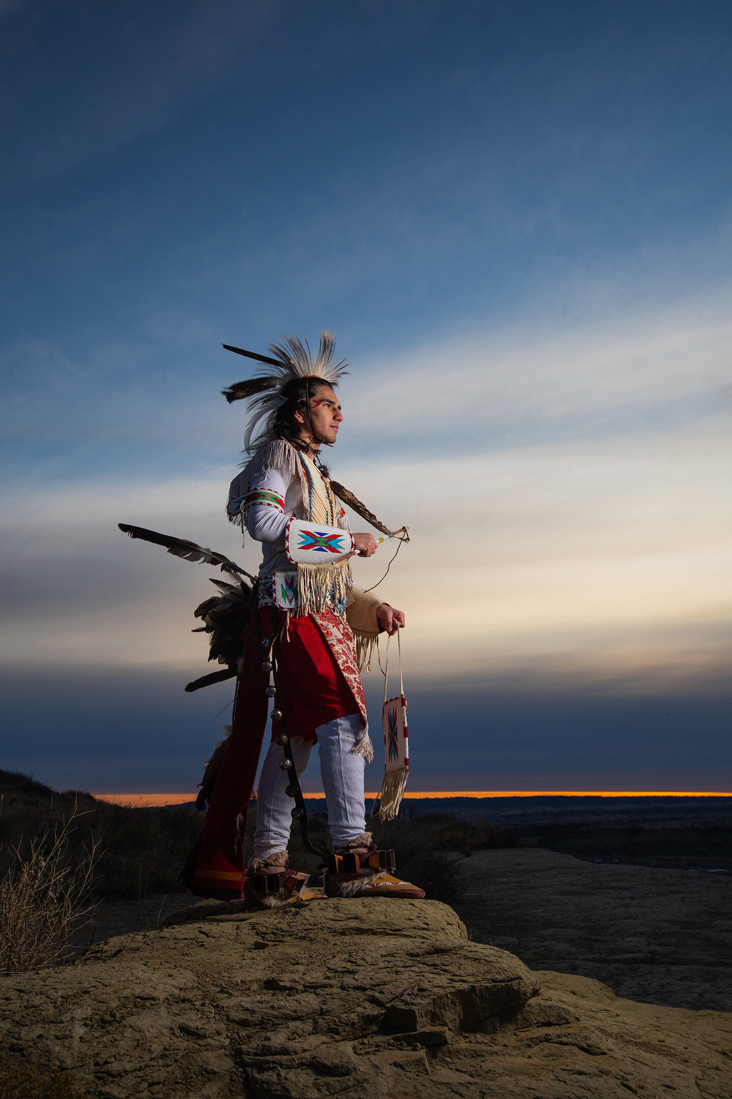 Photographers near me. Native American in traditional Regalia. Picture taken at Swords Park in Billings Montana. Feathers, beading, red and white at sunrise.