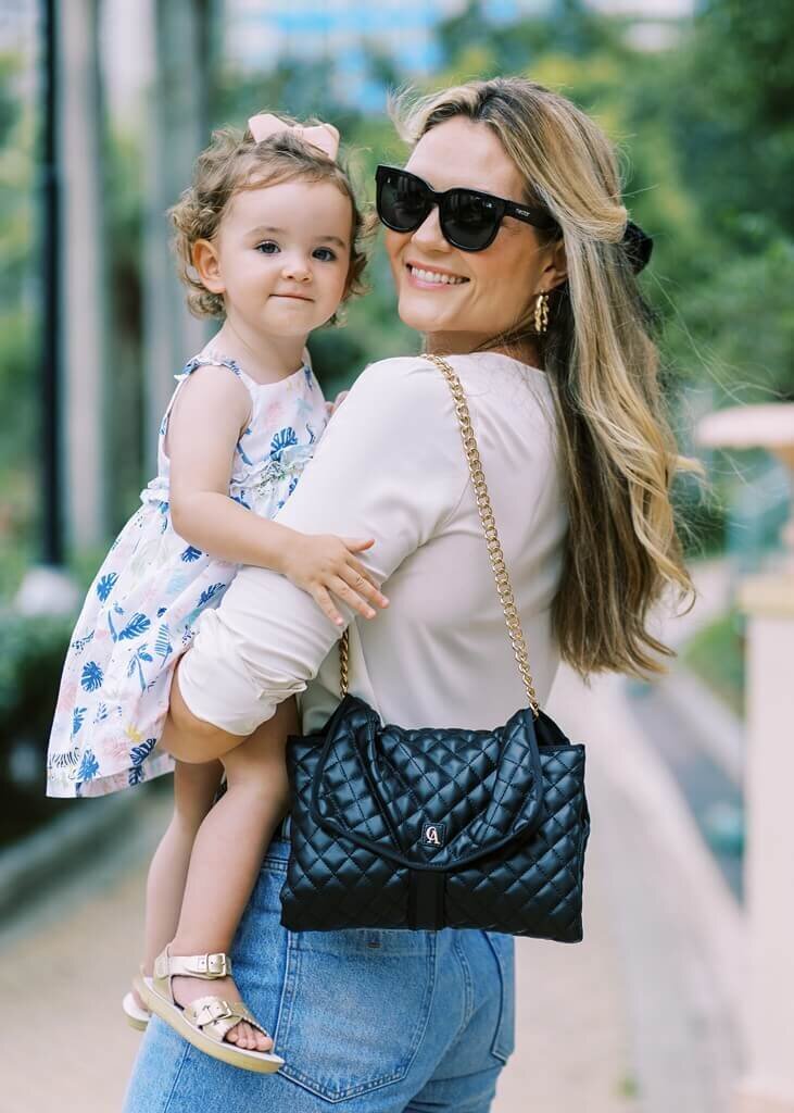 Women looking back, carrying her daughter and a black purse on her shoulder,