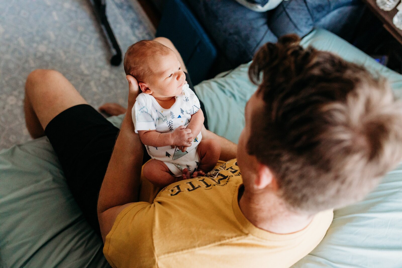 Dad looking at newborn son during family photography session.