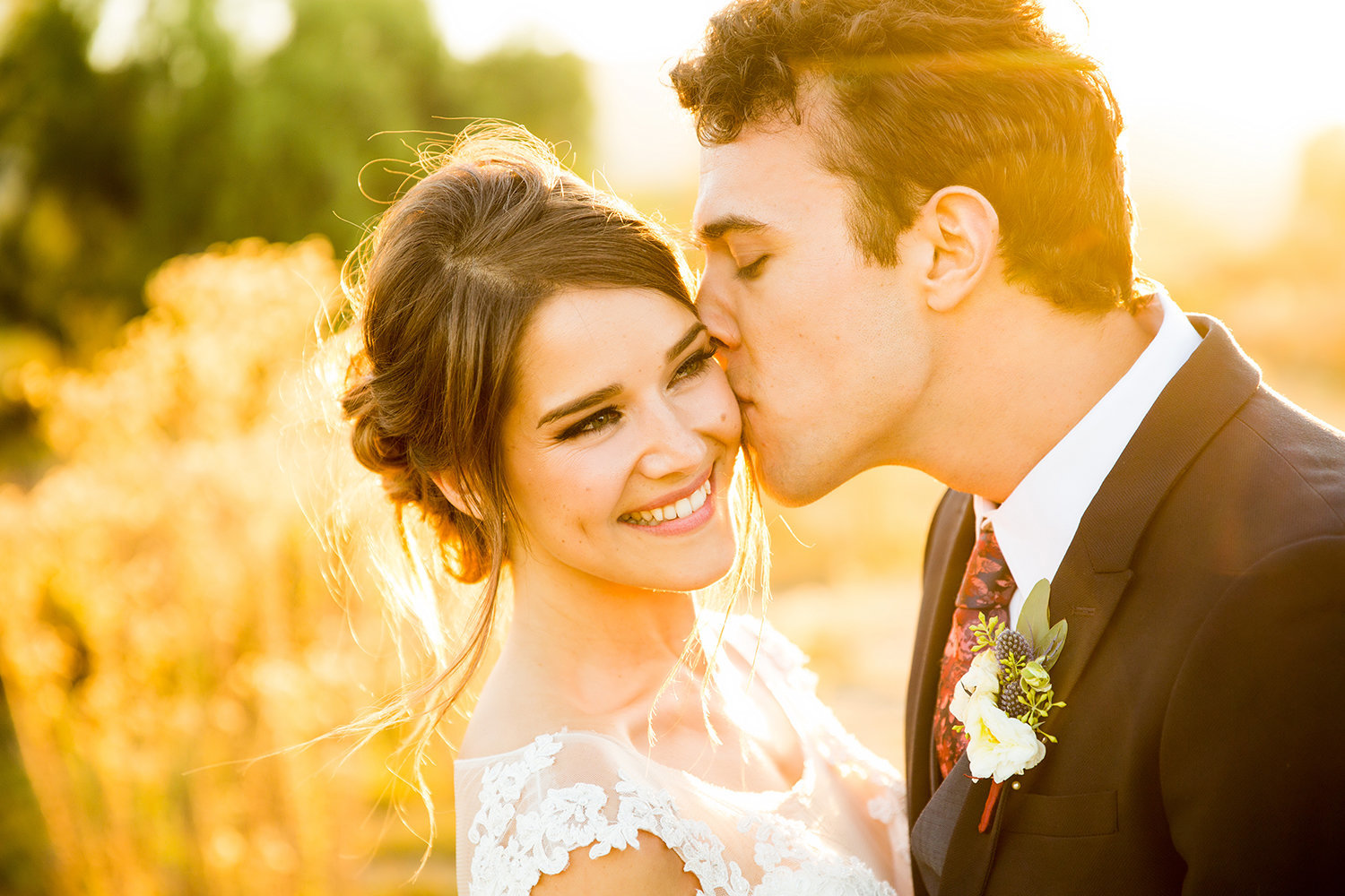 Groom Kissing Bride on the Cheek at Sunset