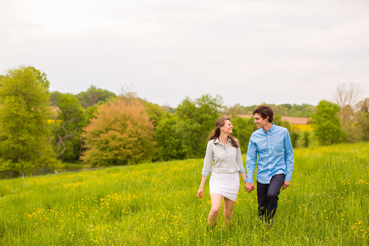 couple walking in a field for engagement photos in maryland