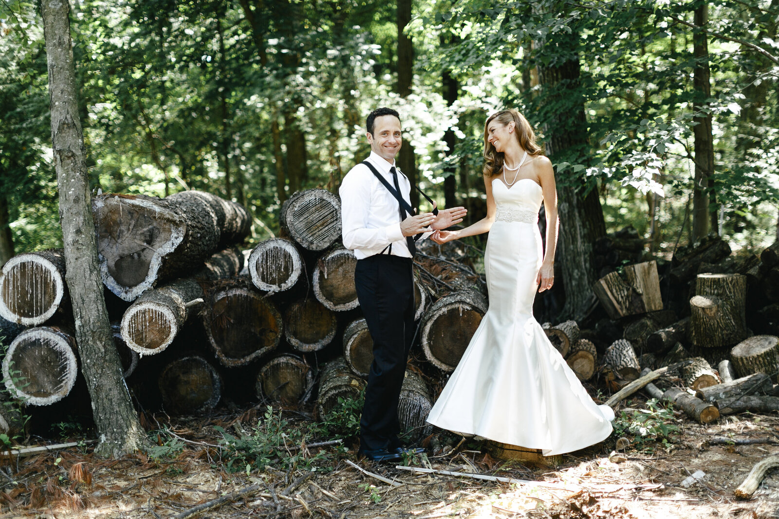 bride and groom with suspenders on farm with woods pile