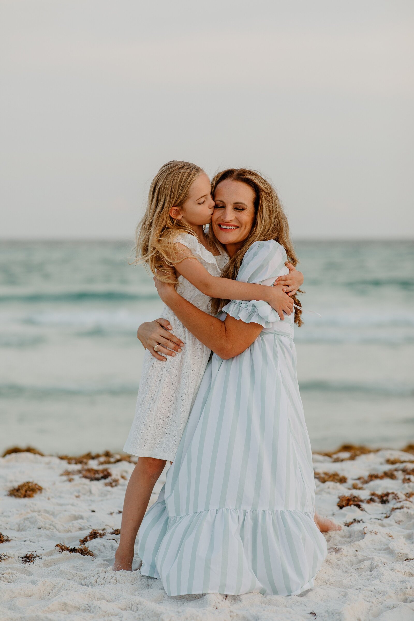 Pensacola Beach vacation family photography session .  Mother and daughter hugging on the beach.