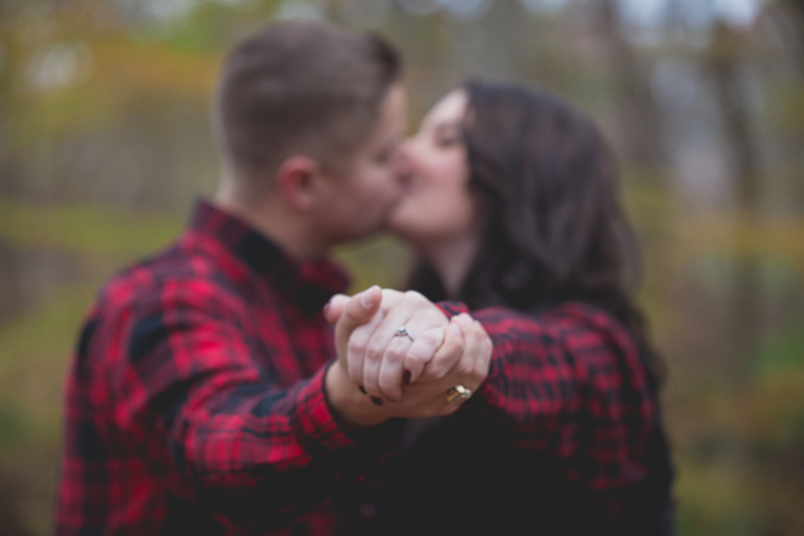 engaged_couple_kiss_while_holding_hands