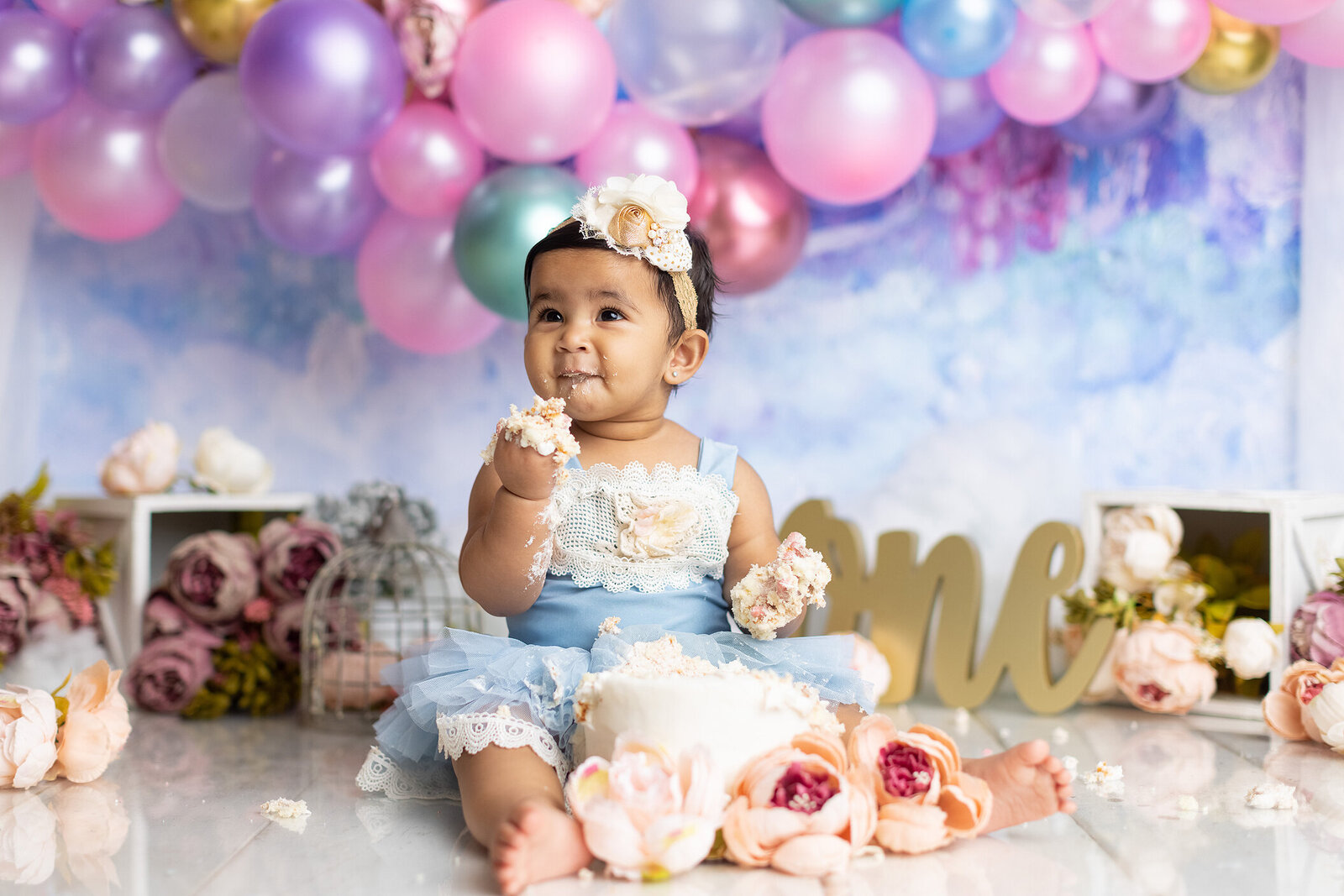 Baby enjoys cake at her 1st birthday photoshoot by a Dallas cake smash photographer.