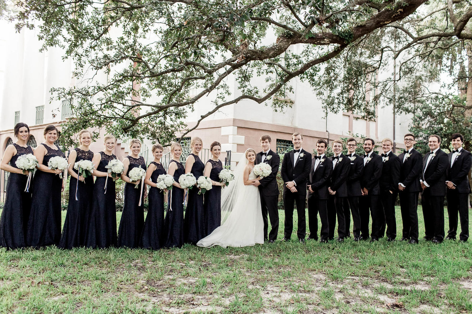 Wedding party stands under trees in Washington Square, Charleston, South Carolina