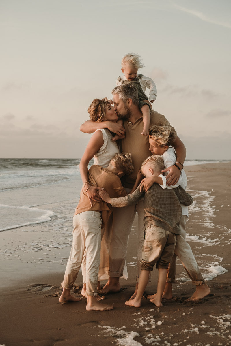 gezin knuffelend op het strand tijdens zonsondergang