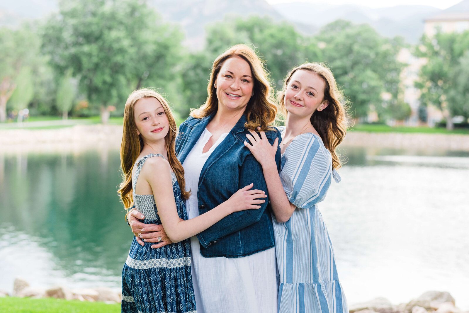 A mother and her two daughters stand in front of a pond during the summer in an image taken by Norther Virginia Family Photographer