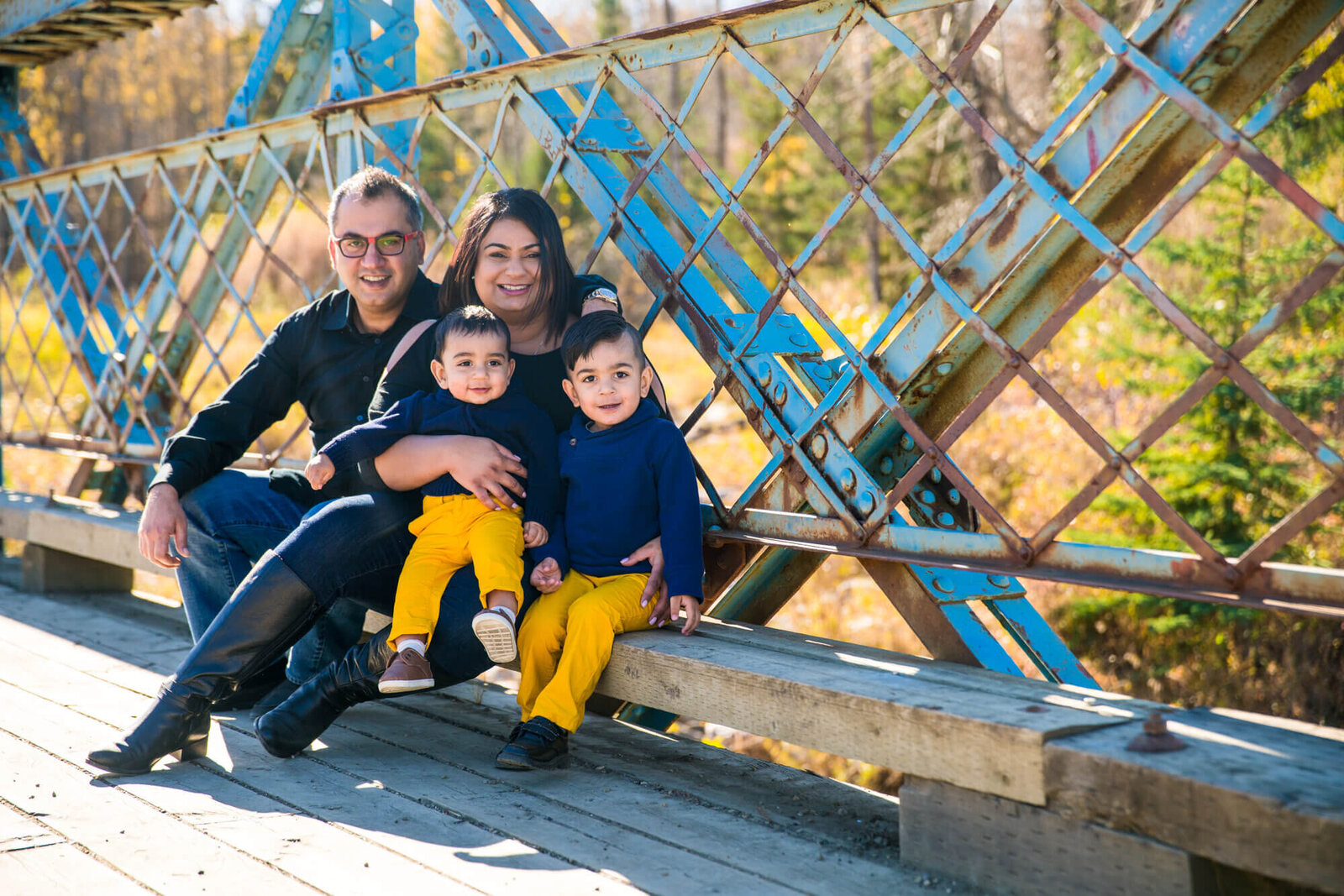 Family of 4 posed on blue  bridge