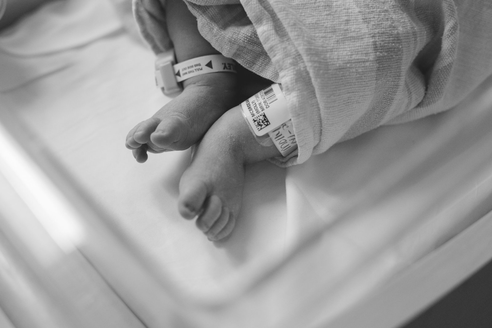 newborn baby lays in bassinet in hospital