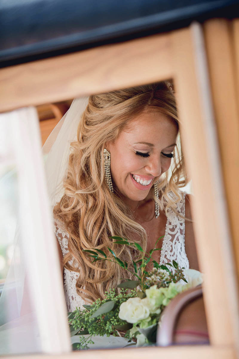 Bride smiles from a window of a vintage car, Destination wedding, Sarasota Garden Club, Florida. Kate Timbers Photography.