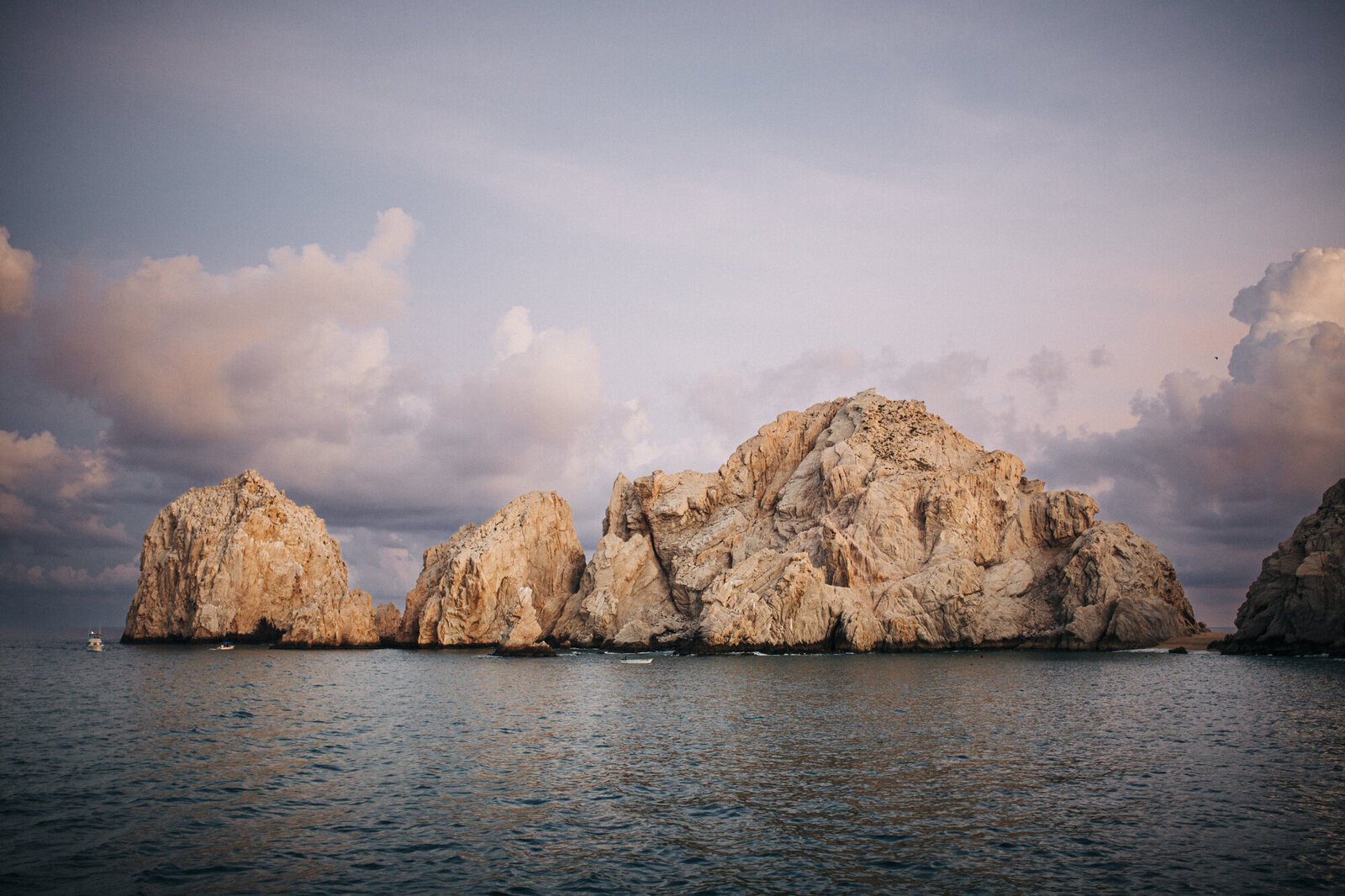 Rocky outcrop by the sea under a cloudy sky at sunset, captured by a traveling wedding photographer.