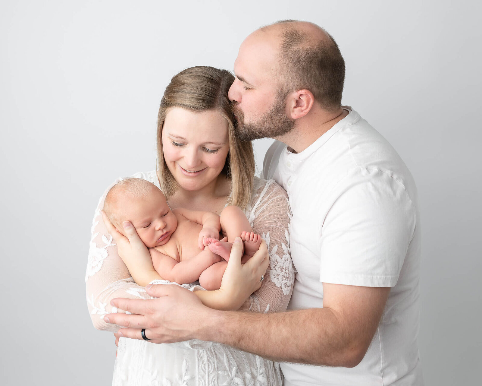 portrait of new parents with  their baby, in photography studio