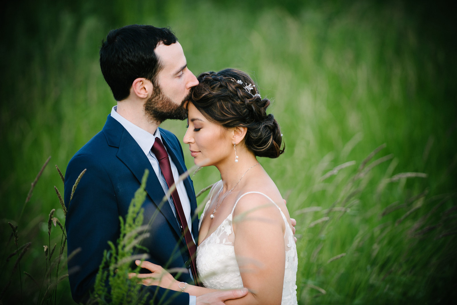 Romantic moment between bride and groom in a field of green