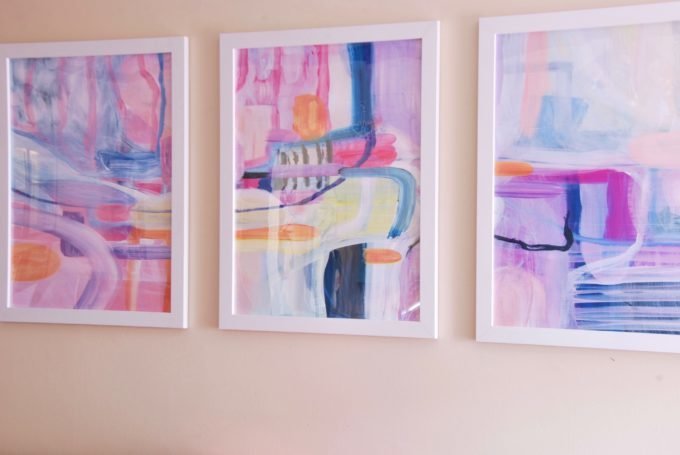 Three white framed pieces of colorful abstract art.