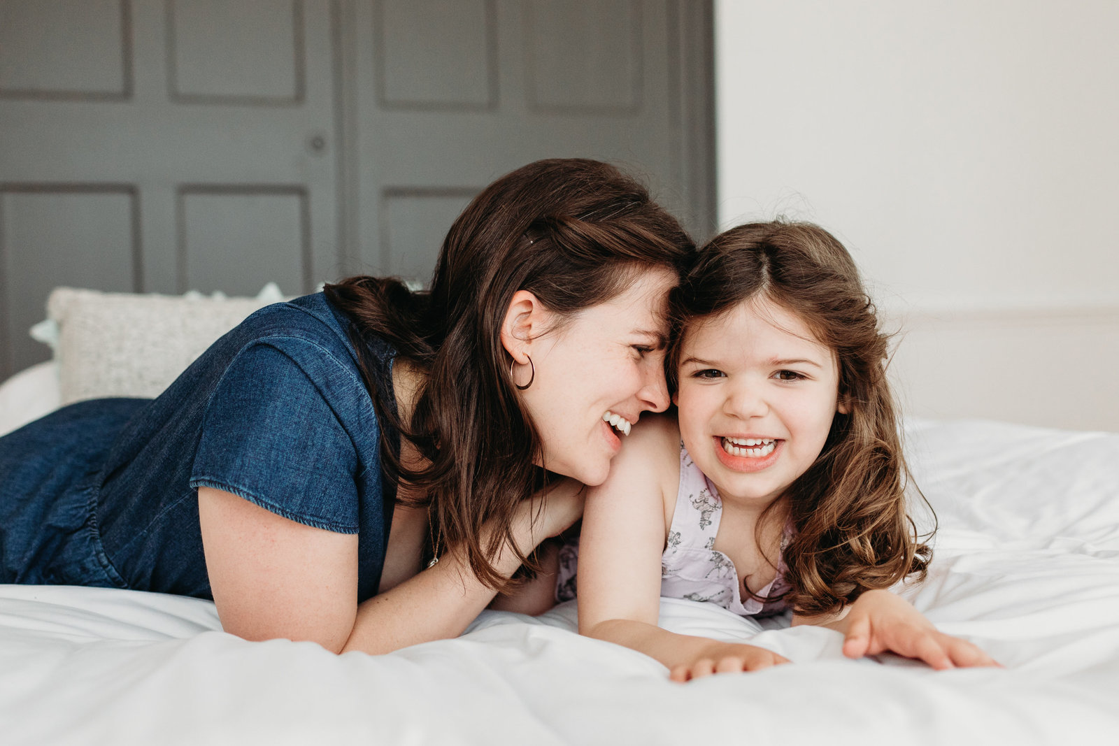 mom snuggles daughter on bed