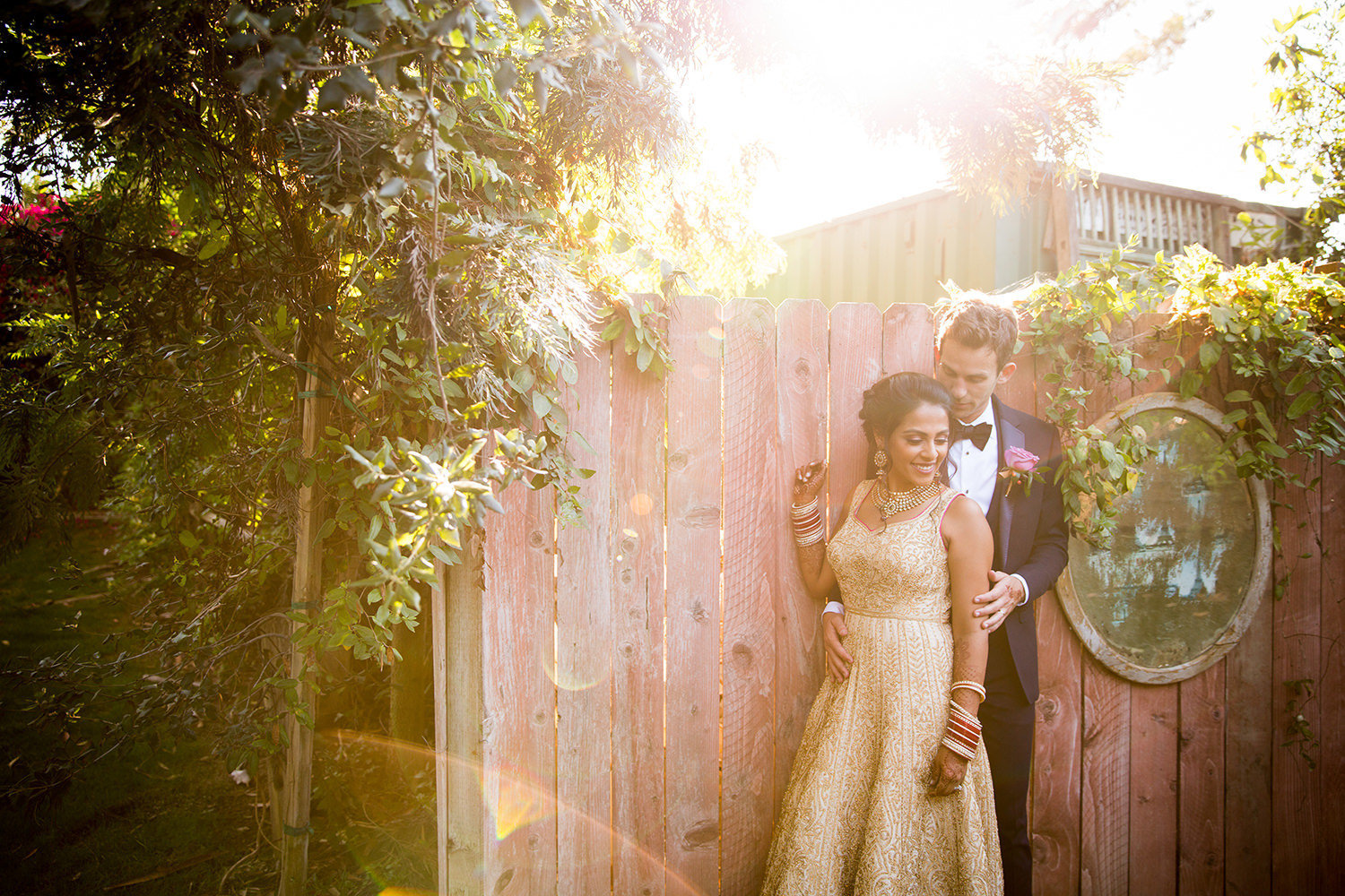 Romantic portrait with lens flare in front of an old fence.