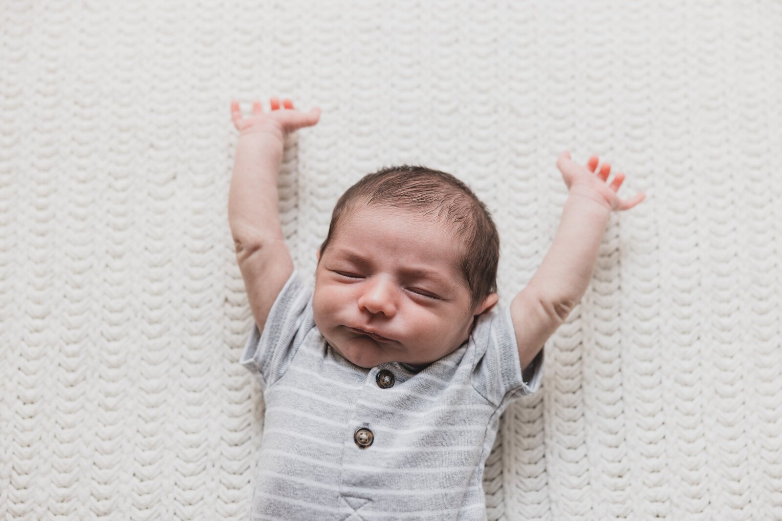 Two week old baby stretching during lifestyle photo session in Pensacola, FL