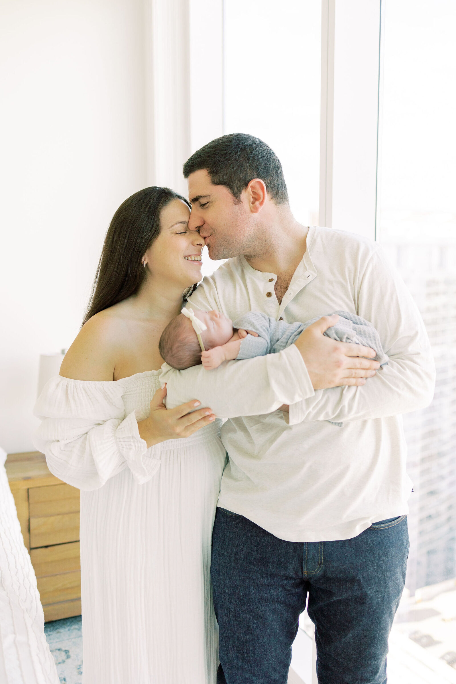 Husband kisses wife on nose during newborn session.