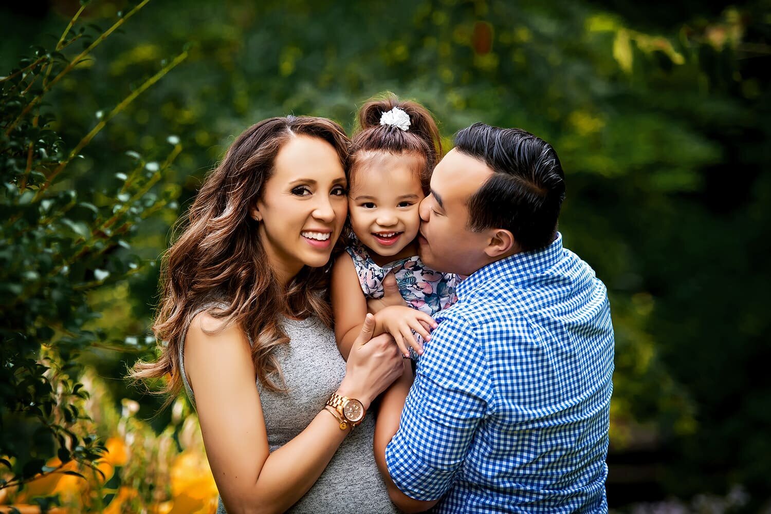 Mother, father and toddler daughter laughing during Queens Park New Westminster family photos.