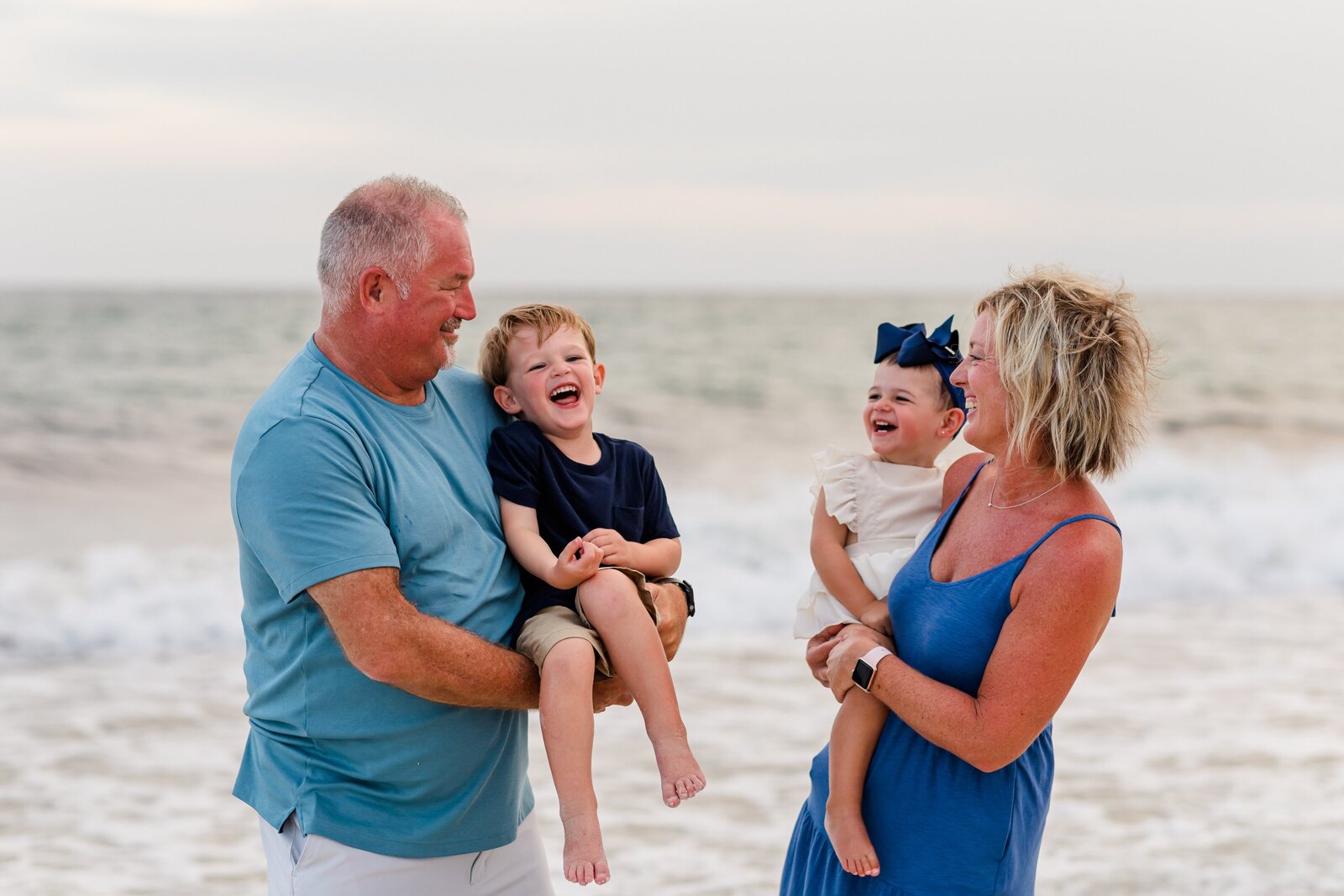 Grandparents playing with grandchildren during beach photo session.