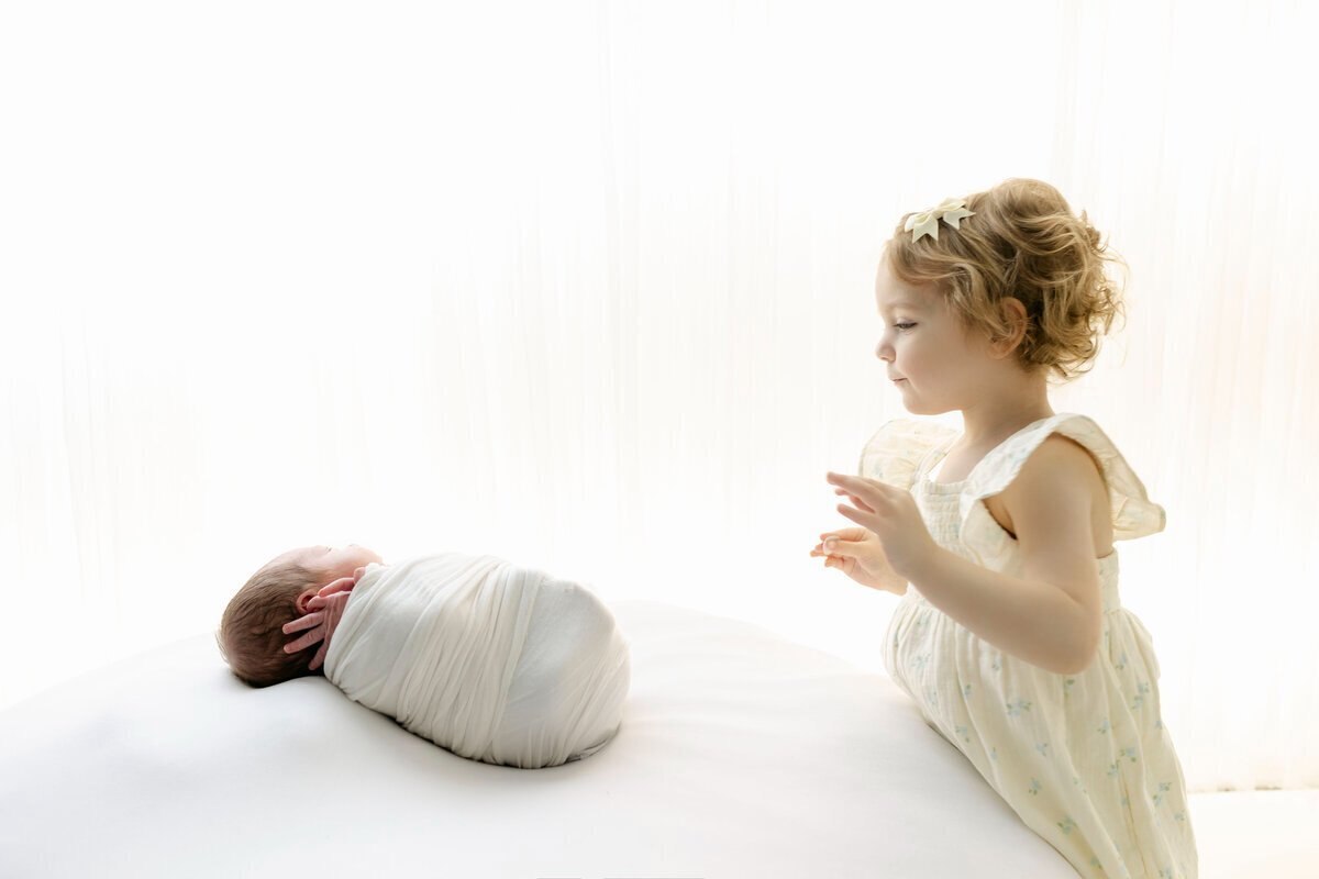 newborn photography nj of little girl looking at newborn baby