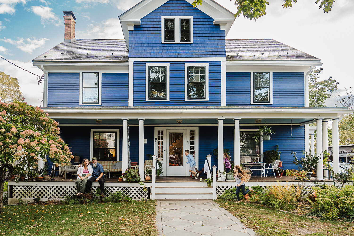 family runs across porch in blue victorian home