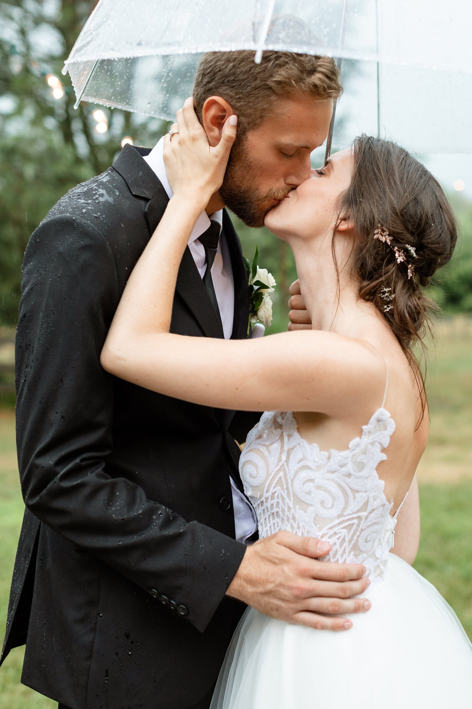 Newly-married-couple-kisses-under-an-umbrella-on-their-rainy-wedding-day-at-arrowwood-farms