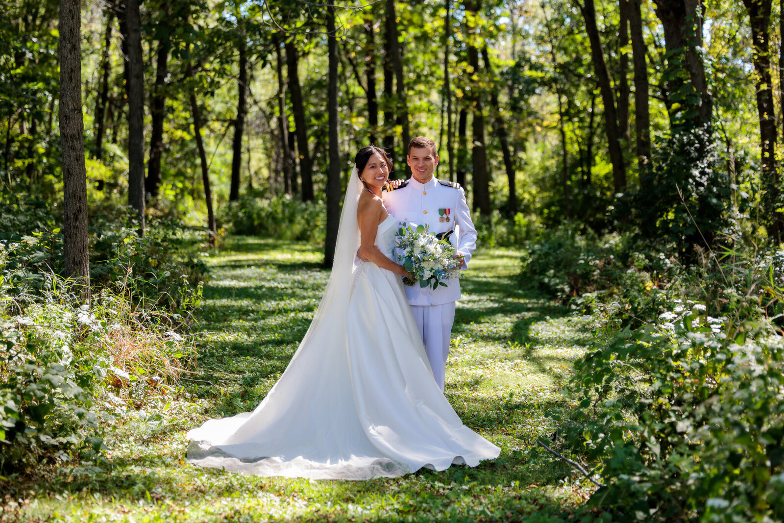 bride and groom smiling sorrounded with tall trees at barnwood events in madison, winconsin.