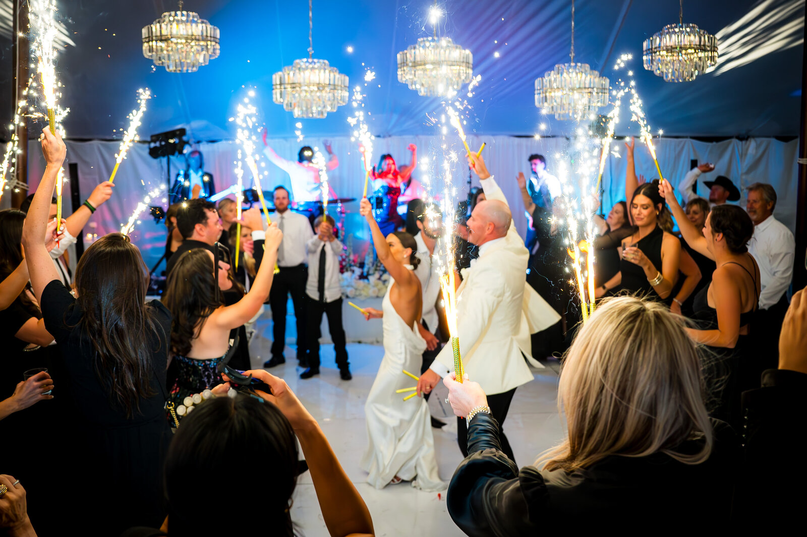 A bride and groom dance with their guests with fireworks in hand at their tented reception in Denver, Colorado.