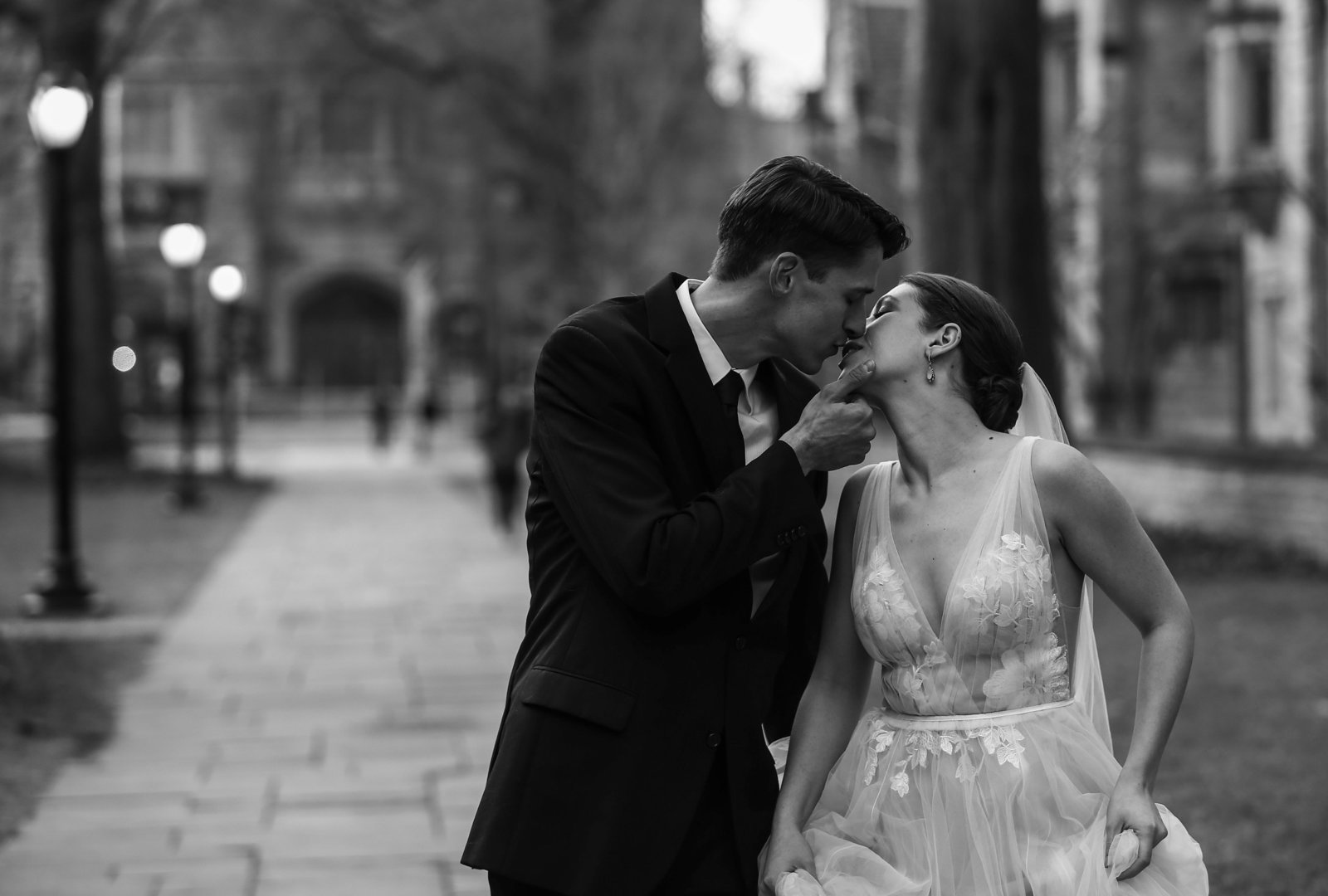 Bride and groom walk together and kiss on Yale University campus